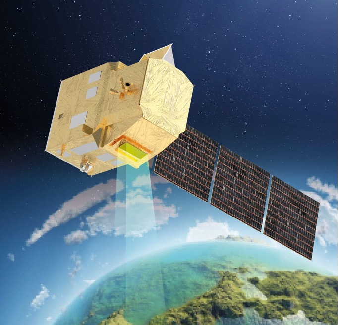 The image is an artist’s impression of the CHIME (Copernicus Hyperspectral Imaging Mission) satellite. The satellite features a box-shaped main body covered in a golden insulating material, equipped with solar panels extending from one side. A beam of light is shown projecting downward from the satellite, indicating its imaging capabilities. The Earth is visible below, showing a detailed section of land and ocean. The background features the dark expanse of space dotted with stars. This satellite image is credited to Thales Alenia Space.