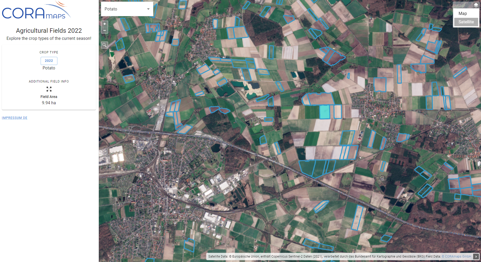 Aerial view of a colorful patchwork of agricultural fields marked with data overlays, alongside urban areas and roads.